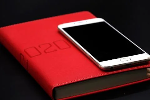 Black Screen Smartphone on the Red Notebook 2020, close up black background Stockfoto's