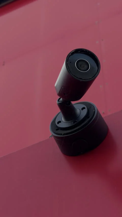Black security camera on adjustable bracket against vivid pink wall with clean Stock Footage 344966161