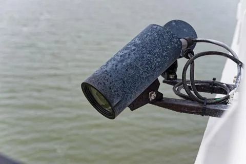 Black security camera mounted on ship with sea background. Stock Photos