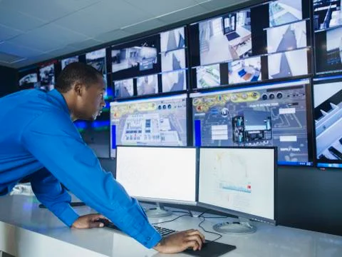 Black security officer watching surveillance cameras Stock Photos
