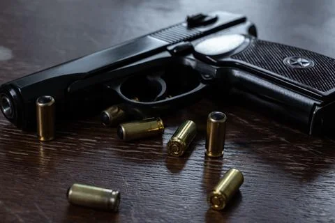 Black semi automatic pistol with rubber bullet cartridges on wooden table Fotos Stock