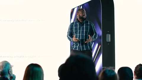 Black senior designer introduces new smartphone to participants Stock Footage 328129376