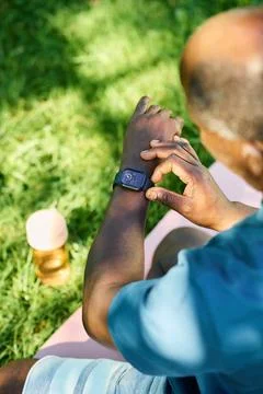 Black Senior Man Checking Smartwatch Outdoors in Park Foto stock