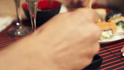 Black sesame sushi roll dipped into soy sauce with chopsticks. Stock Footage 345447708