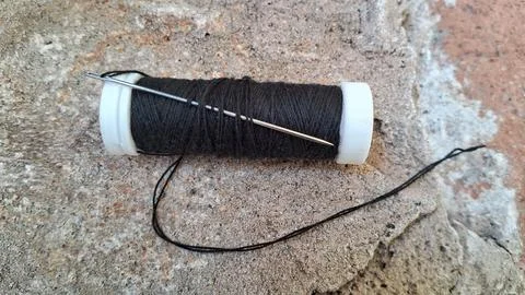 Black sewing thread on a spool with needle. Tailoring equipment for garment Stock Photos
