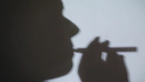 Black shadow of Human on white wall. Female smokes. Stock Footage 142319147