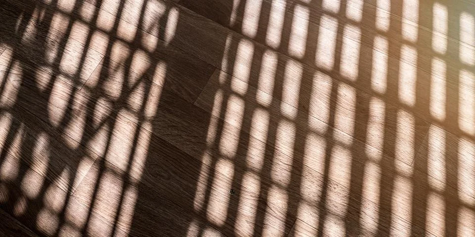 Black shadows from sunlight through window falling on wooden floor Stock Photos
