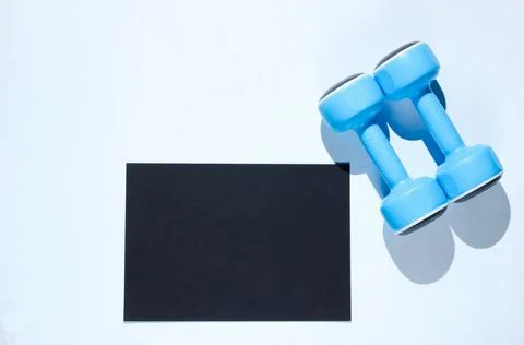 Black sheet of paper for copy space, plastic dumbbells on a gray background.  库存照片