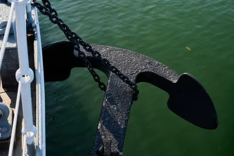 Black ship anchor mounted on deck edge over green sea water, Gdynia, Pomerani Stock Photos