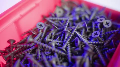 Black short self-tapping screws in a red plastic container spinning close-up Stock Footage 170471111