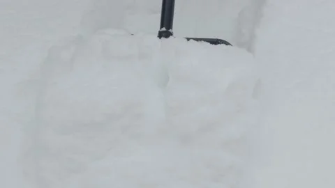 A black shovel using to clear a patch of white snow. Close-up Stock Footage 325962770