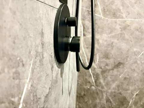 Black showerhead on a marble wall. Stock Photos