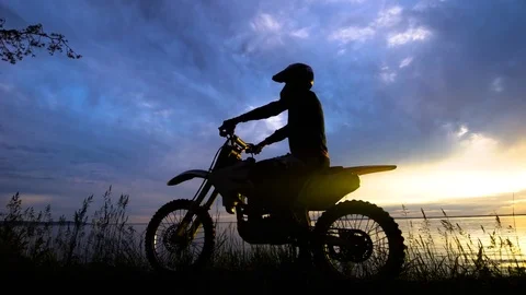 Black silhouette of man posing on motorcycle in sunset Video stock 78041196