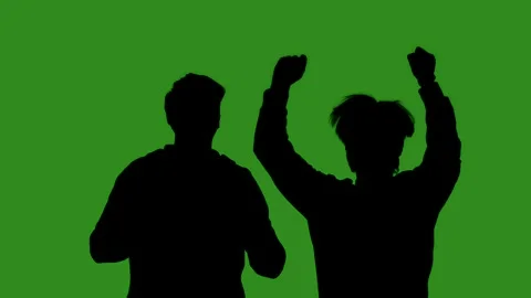 Black silhouettes of two men celebrating victory against a green chroma key Stock Footage 334170341