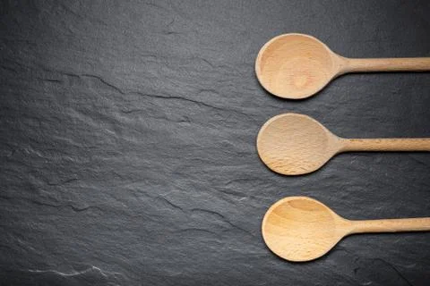 Black slate board for serving with three wooden spoons, top view Stock Photos