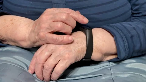 The black smart band with display touchpad and heart rate monitor. The old woman Stock Footage 325530842