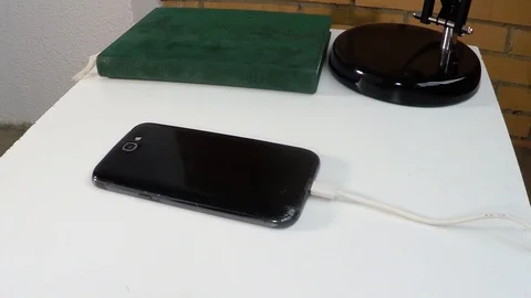 Black smartphone explodes while charging on white table. Fisheye action camera Stock Footage 125438819