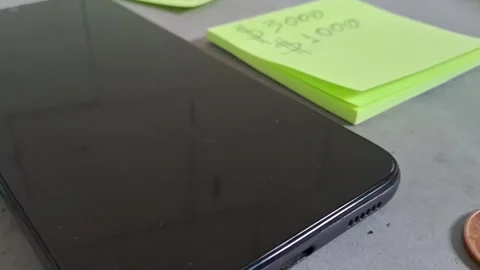 Black smartphone with paper notes and currency in motion footage 動画素材 339248311