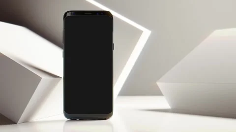 Black smartphone standing on white surface with abstract geometric shapes with Stockbeeldmateriaal 344635011