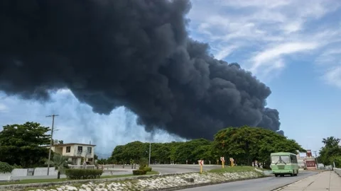 Black smoke billowing from an exploding fuel tank above the buildings Stock Footage 214965147