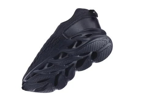Black sneaker with a rubber ribbed structural sole on a white background. Stock Photos