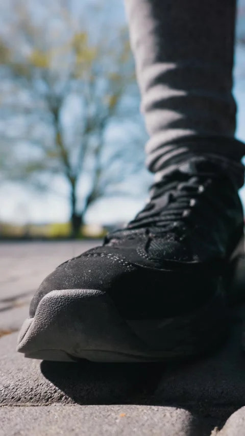 Black Sneaker Stepping Forward Onto Paved Ground in an Outdoor Park Vidéo 334126749
