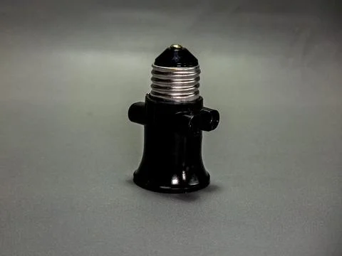A black socket adapter isolated on a gray surface, featuring a glossy dark .. Stock Photos