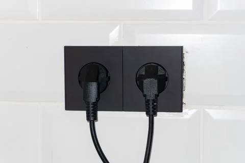 Black Sockets in the wall, wires in the socket on the kitchen wall, overloaded Stock Photos