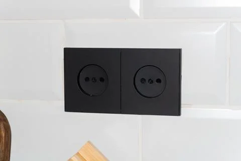 Black Sockets in the wall, wires in the socket on the kitchen wall, overloaded Stock Photos