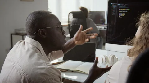 Black Software Developer Explaining Code to Colleague in Office 库存影片 348150771