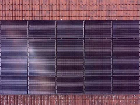 Black solar panels in rectangular form installed on a tiled roof 스톡 사진