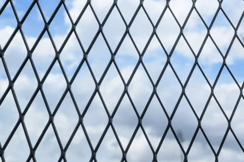 Black solid metallic mesh fence closeup with sky in the background. Foto stock