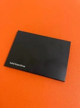 Black Solid State Drive SSD closeup view on orange background focus on foregr Stock Photos