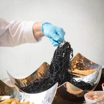 Black spaghetti in hand chef Stock Photos