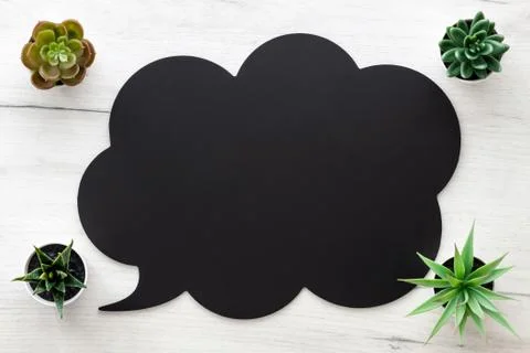 Black speech bubble with space for text on white wooden table. Copy space. Stock Photos