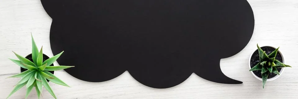 Black speech bubble with space for text on white wooden table. Copy space. Stock Photos