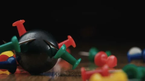 Black spherical magnet falling onto pins group on wooden floor Stock Footage 142677144