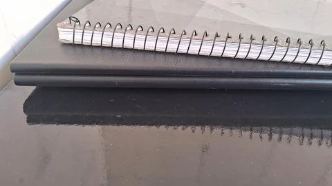 Black spiral bound notebook resting on top of dark laptop Stock Photos