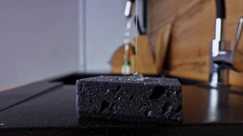 A black sponge lying on a black granite sink Stock Footage 299792992