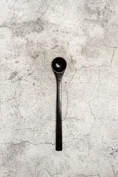 A black spoon on a gray stone kitchen counter background with copy space Stock Photos