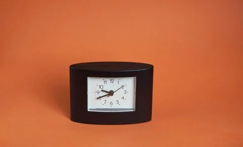 Black square clock on light brown background Stock Photos