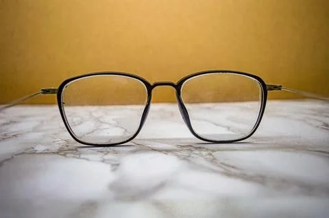 Black square eyeglasses with subtle dust on clear lenses placed over marble.. Fotos Stock