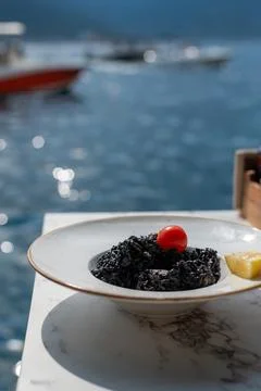 Black squid ink risotto garnished with a cherry tomato and lemon 库存照片