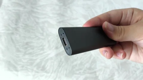 Black ssd external drive for PC, laptop in a womans hand. Flash drive, memory Stock Footage 313980086