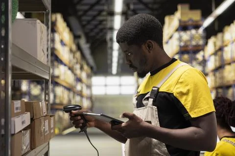 Black staff member using a barcode scanner to process shipping labels on boxes Stock Photos
