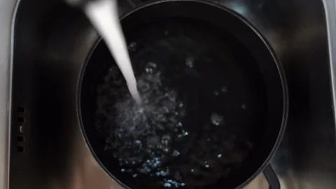 Black stainless cooking pan lying in the sink and pure water flowing in it Stock-Footage 126005251