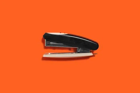 Black stapler isolated on the orange background Stock Photos