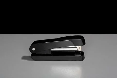 Black stapler sitting on a table. Stock Photos