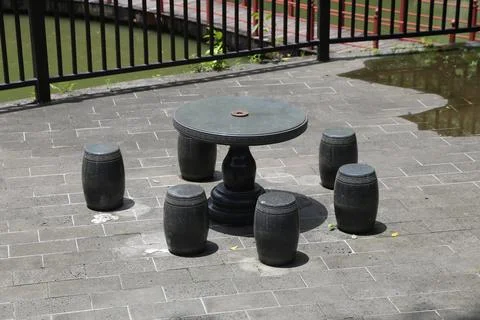 A black stone round table with four black short stools, on the street of a .. Stock Photos