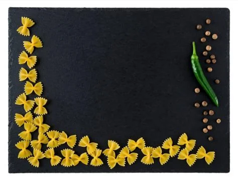 Black stone serving board with raw farfalle, allspice and green chili pepper Stock Photos
